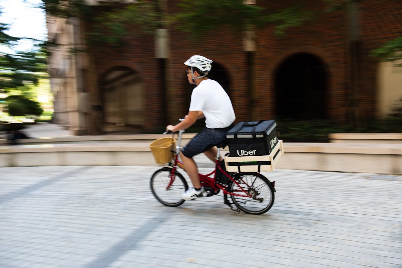 A man on a bicycle delivering food in a city, showcasing urban transportation.